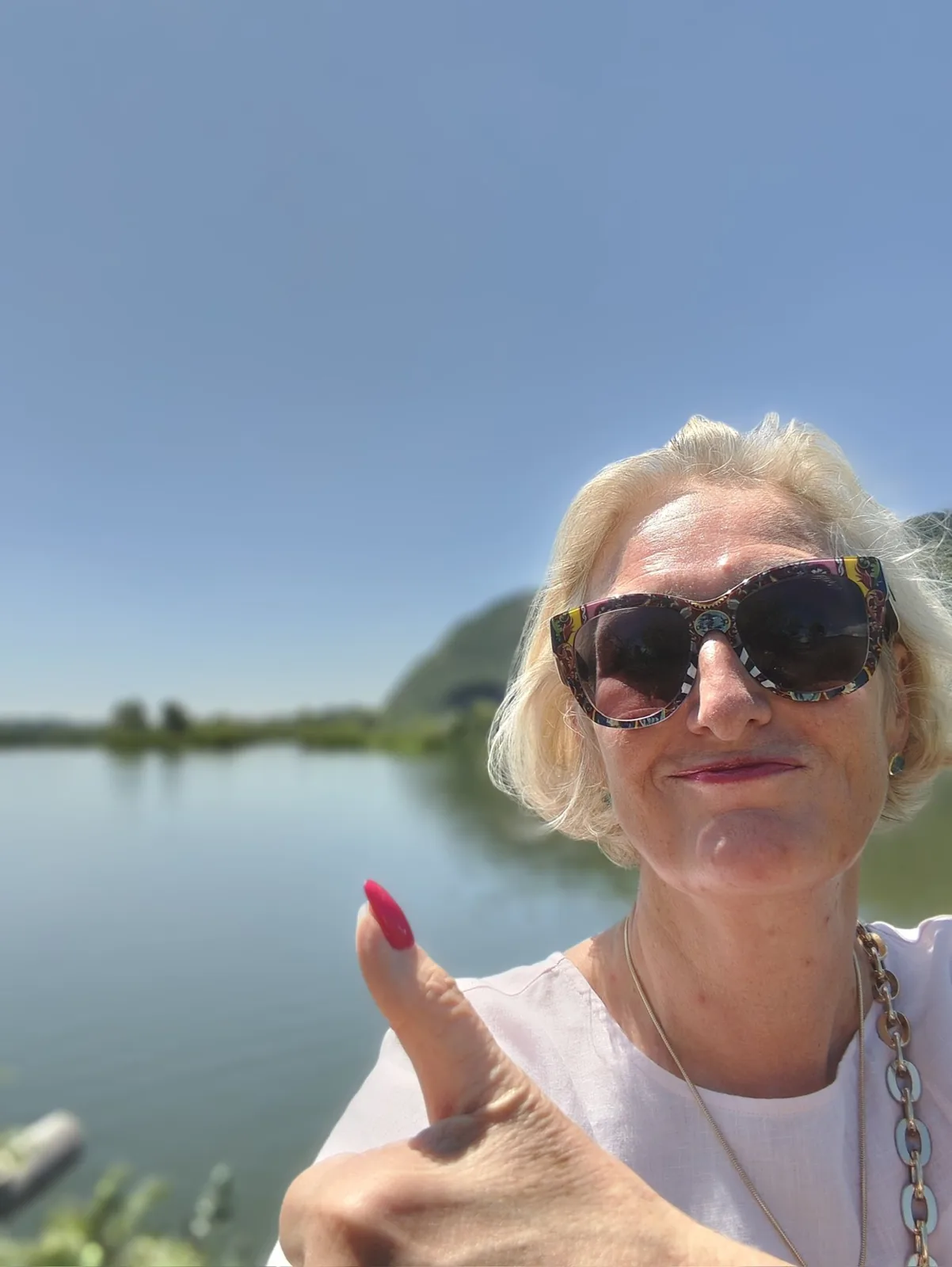 Kirsten Peter mit Sonnenbrille, Daumen hoch, am See